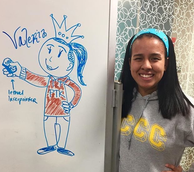 Velaria standing next to a white board with a drawing on it.