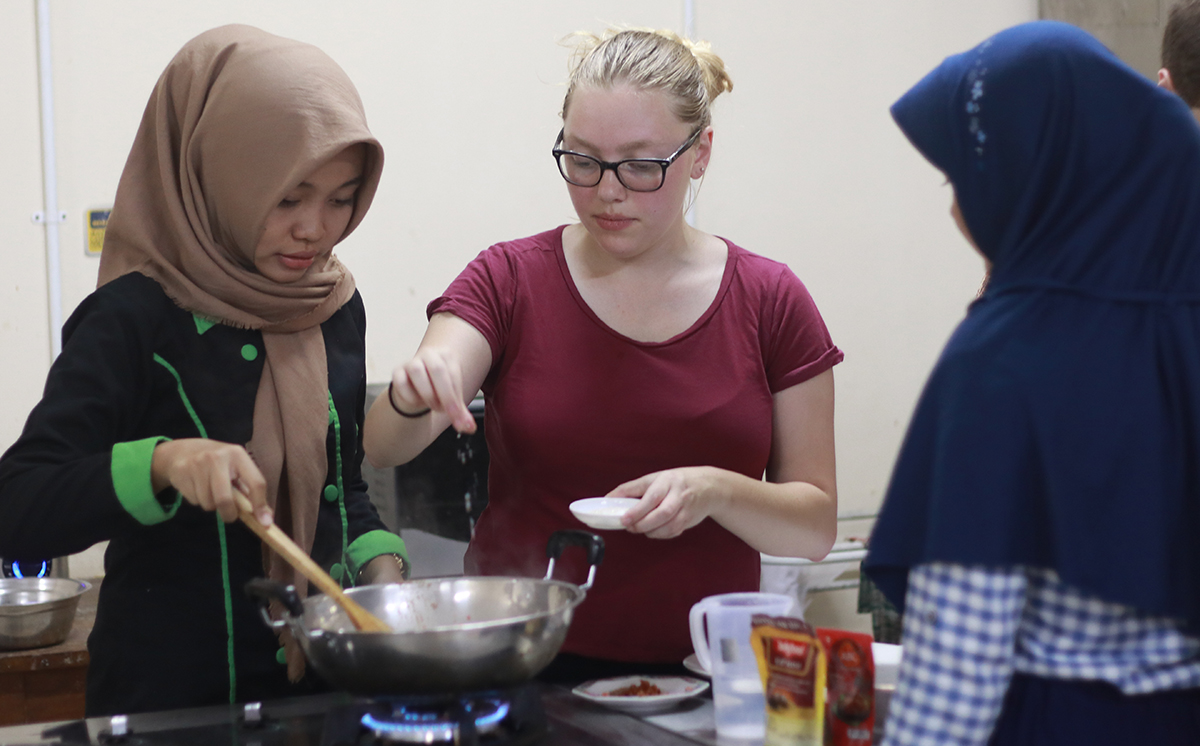 Mikaila Cordeau (center) adds a pinch of salt to a meal while in Indonesia.
